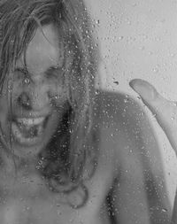 Close-up of screaming woman seen through wet glass window