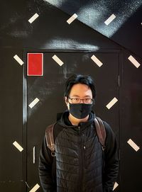 Portrait of young man standing against wall