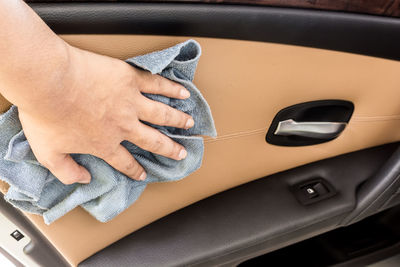Close-up of human hand cleaning car door