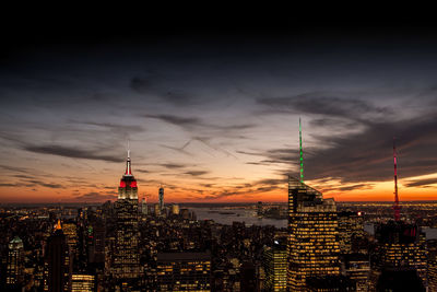 Illuminated buildings in city against sky during sunset