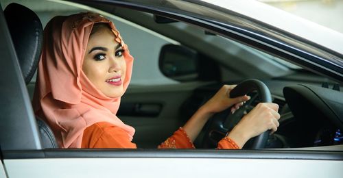 Portrait of young woman using smart phone in car
