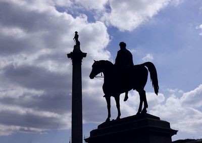 Low angle view of silhouette statue against cloudy sky