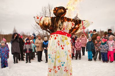 People looking at burning human representation during winter