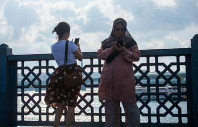 People standing on railing against sky