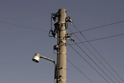 Low angle view of electricity pylon against blue sky