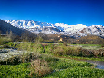 Scenic view of snowcapped mountains against blue sky