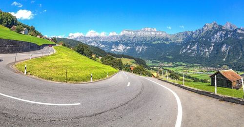 Scenic view of road by mountains against clear sky