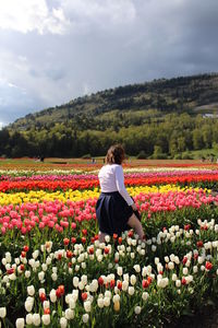 Woman walking in tulip farm against mountain