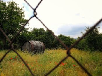 Scenic view of field against sky seen through chainlink fence