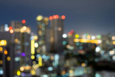 Defocused image of illuminated city against sky at night