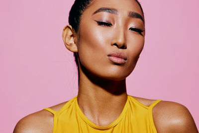 Close-up of young woman against pink background