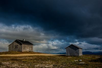 House on field against dramatic sky