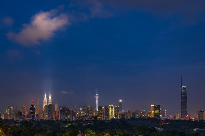 Illuminated cityscape against sky at night