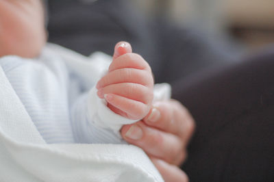 Cropped image of person holding baby hand