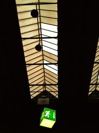 Low angle view of illuminated sign hanging on ceiling in building