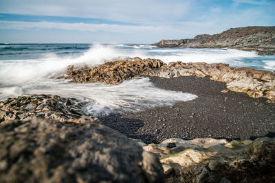 Scenic view of rocks on beach against sky