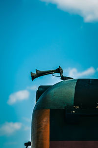 Low angle view of rusty metal against blue sky