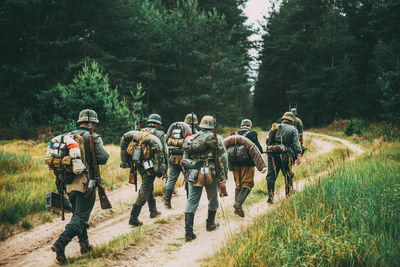 Rear view of soldiers walking on trail in forest