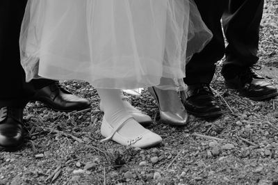 Low section of bride and groom standing on field