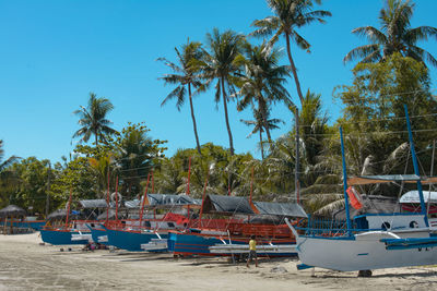 Boats moored in sea against clear blue sky