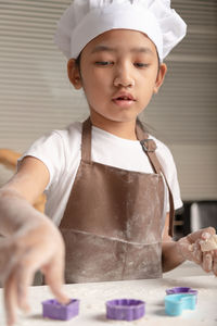 Cute girl holding cookie cutter at home