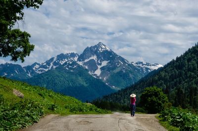 Rear view of man walking on road in forest