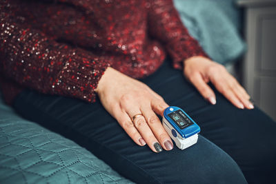 Woman measuring the degree of oxygen saturation of the blood at home using pulse oximeter