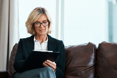 Smiling businesswoman using digital tablet while sitting on sofa at home