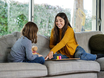 Mother and daughter sitting on sofa