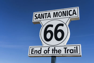 Close-up of road sign against blue sky