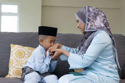 Rear view of mother and daughter sitting on floor