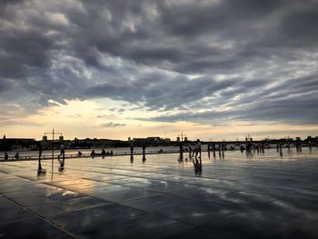 Scenic view of wet city against sky during sunset