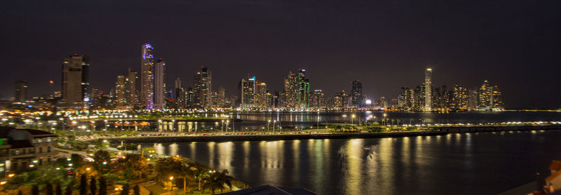 Illuminated modern buildings in city against sky at night