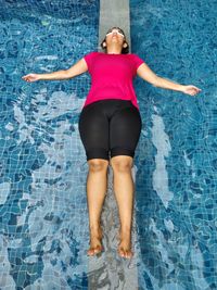 Full length of woman lying in swimming pool