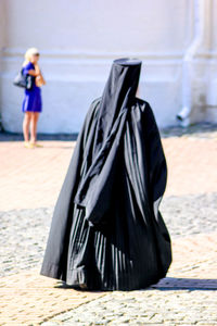 Rear view of woman in religious dress walking on cobbled footpath