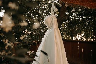 Beautiful wedding dress with pleats and tail hanging on white hanger outdoors. ballgown 