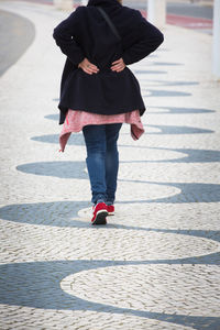 Low section of woman standing on footpath