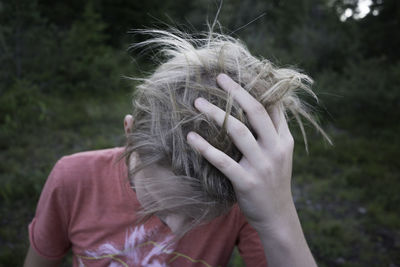 Close-up of boy with hand in hair on field
