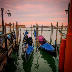 Boats moored in sea at sunset