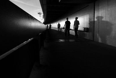 Silhouette people walking in tunnel