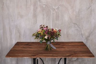 Flower vase on table against wall