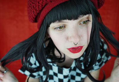 Close-up of young woman sitting against red wall