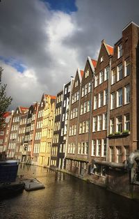 Canal in city against sky