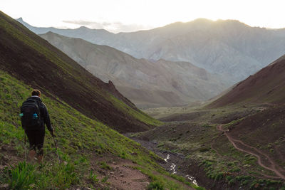 Rear view of backpacker standing on mountain during sunset