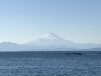 Scenic view of sea and mountains against clear blue sky