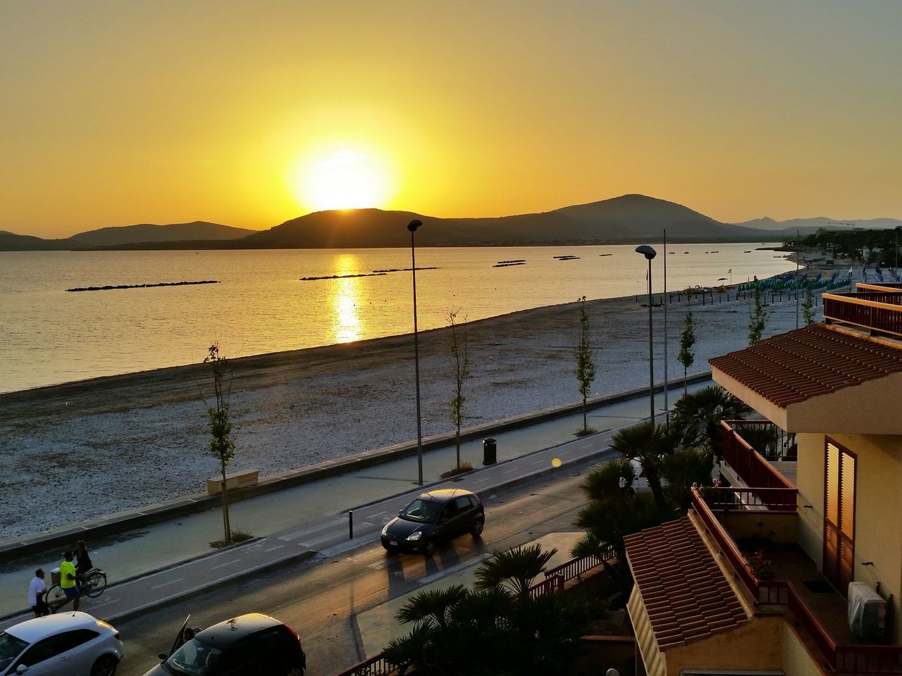 sunset, water, transportation, sun, orange color, mode of transport, sea, mountain, nautical vessel, clear sky, sunlight, beauty in nature, scenics, built structure, moored, boat, car, architecture, nature, building exterior