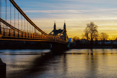 Bridge over river against sky during sunset