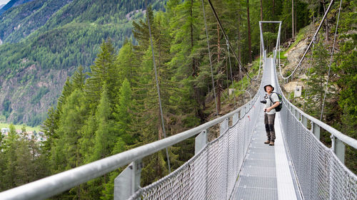 Woman walking on footbridge in forest