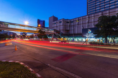 Light trails on city street by buildings at night