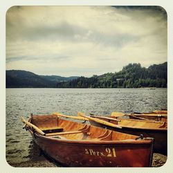 Boats in lake against cloudy sky